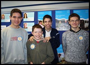 4 teenage boys standing infront of a wall display